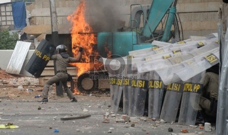 Petugas kepolisian bersama Satpol PP berusaha memukul mundur massa yang membakar alat berat ketika terlibat kericuhan saat penggusuran Kampung Pulo,, Jatinegara, Jakarta, Kamis (20/8).   (Republika/Yasin Habibi)