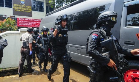 Petugas kepolisian bersenjata lengkap bergegas keluar seusai berhasil menangkap terduga teroris di Kantor Kelurahan Arjuna, Bandung, Jawa Barat, Senin (27/2).