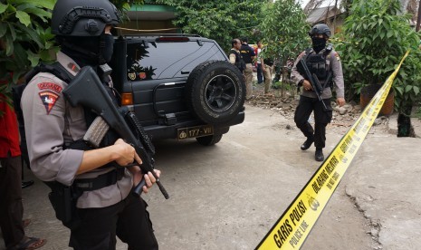 Petugas kepolisian bersenjata lengkap berjaga di rumah pelaku teror polisi saat dilakukan penggeledahan, di Sepatan, Kabupaten Tangerang, Banten, Kamis (20/10). 