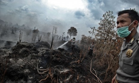 Petugas Kepolisian berusaha memadamkan kebakaran lahan gambut yang terjadi di Desa Rimbo Panjang, Kampar, Riau, Senin (29/8). 