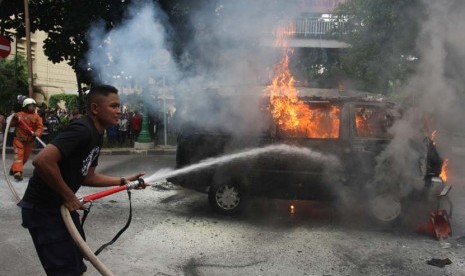 Petugas Kepolisian berusaha memadamkan sebuah mobil dengan nopol B 2791 AJ yang terbakar di depan Mabes Polri, Jakarta, Rabu (4/2). (ANTARA/Reno Esni)