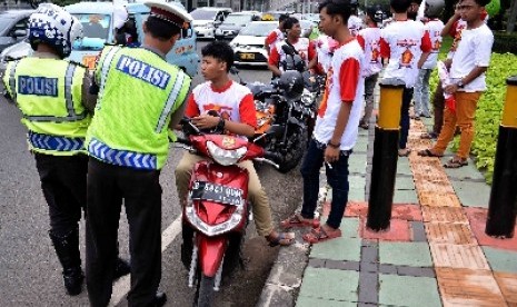 Petugas kepolisian lalu lintas menilang simpatisan partai saat kampanye di kawasan Gatot Subroto, Jakarta.