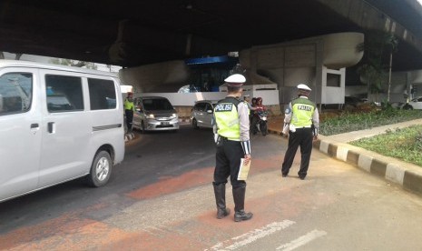 Petugas kepolisian melakukan operasi ganjil-genap di kawasan Pancoran, Jakarta Selatan, Rabu (1/7). Hingga siang hari, telah lebih dari 200 surat tilang dikeluarkan.