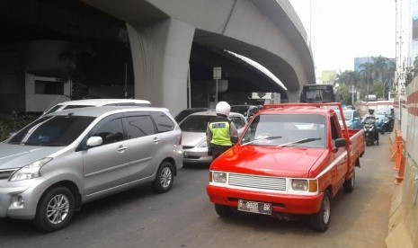 Petugas kepolisian melakukan operasi ganjil-genap di kawasan Pancoran, Jakarta Selatan, Rabu (1/7). Hingga siang hari, telah lebih dari 200 surat tilang dikeluarkan.