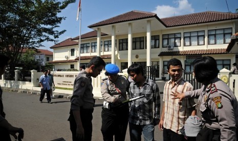 Petugas kepolisian melakukan pemeriksaan terhadap pengunjung saat digelar sidang teroris bom Beji di Pengadilan Negeri kota Depok, Jawa Barat, Senin (24/6). Pengamanan tersebut untuk mengantisipasi kejadian yang tidak diinginkan saat vonis bagi terdakwa Ag