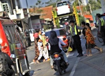 Petugas kepolisian membantu pengguna jalan yang akan menyeberang di pasar Gebang, Cirebon, Jawa Barat.