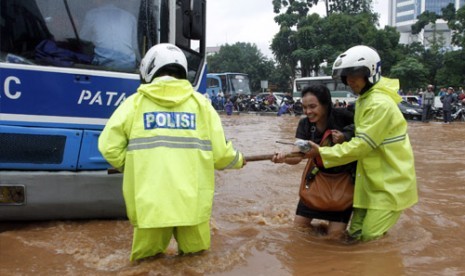  Petugas Kepolisian membantu seorang perempuan yang mencoba melintasi banjir yang merendam di kawasan Tosari Jakarta Pusat, Kamis (17/1).