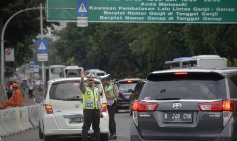 Petugas Kepolisian memberhentikan kendaraan dan memberikan imbauan kepada pengendara berplat nomor genap saat melintas di Kawasan Pembatasan Lalu Lintas Ganjil Genap, Medan Merdeka Barat, Jakarta, Jumat (26/8).