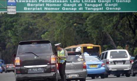 Petugas Kepolisian memberhentikan kendaraan dan memberikan imbauan kepada pengendara berplat nomor genap saat melintas di Kawasan Pembatasan Lalu Lintas Ganjil Genap, Medan Merdeka Barat, Jakarta, Jumat (26/8). 