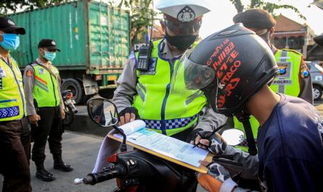 Petugas kepolisian memberikan sanksi surat teguran kepada pengendara motor dari luar Sidoarjo saat penerapan Pembatasan Sosial Berskala Besar (PSBB) di titik pemeriksaan Pos Polantas Waru, Sidoarjo, Jawa Timur, Sabtu (2/5/2020). PSBB di Surabaya Raya yang meliputi Kota Surabaya, Kabupaten Sidoarjo dan Kabupaten Gresik memberlakukan sanksi bagi pengendara yang melanggar.