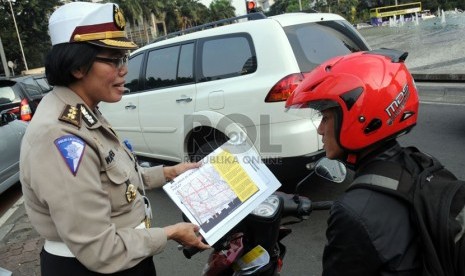 Petugas kepolisian memberikan sosialisasi tentang pengalihan arus lalu lintas saat hari pengumuman rekapitulasi suara Pilpres 2014-2019 di kawasan Bundaran HI, Jakarta, Jumat (18/7). (Republika/Aditya Pradana Putra)