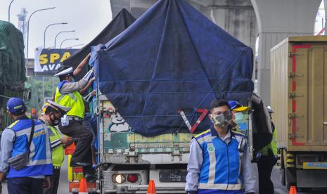 Petugas kepolisian memeriksa muatan truk yang melintas di tol Jakarta-Cikampek di Cikarang Barat, Kabupaten Bekasi, Jawa Barat, Sabtu (2/5/2020). Menurut data Ditlantas Polda Metro Jaya, sebanyak 7.748 kendaraan dipaksa putar balik menuju lokasi asal akibat terjaring razia Operasi Ketupat 2020. 