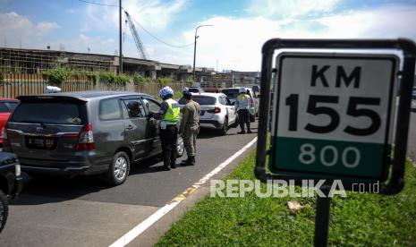 Petugas kepolisian memeriksa surat keterangan sehat dari pengendara yang keluar di Gerbang Tol Cileunyi, Kabupaten Bandung, Jawa Barat, Kamis (11/2/2021). Pemeriksaan yang dilakukan kepada pengendara dari luar Kota Bandung tersebut digelar dalam rangka Penerapan Pembatasan Kegiatan Masyarakat (PPKM) berskala mikro guna mewujudkan Kabupaten Bandung zona hijau COVID-19. 