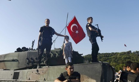 Petugas kepolisian menduduki kendaraan militer yang digunakan kudeta, setelah sejumlah personel militer pro-kudeta menyerahkan diri di Jembatan Bosphorus Istanbul, Sabtu (16/7).