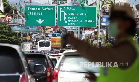  Petugas kepolisian mengatur kendaraan menuju puncak yang terjebak kemacetan di Simpang Gadog, Bogor, Jawa Barat, Jumat (6/5). (Republika/Rakhmawaty La'lang)