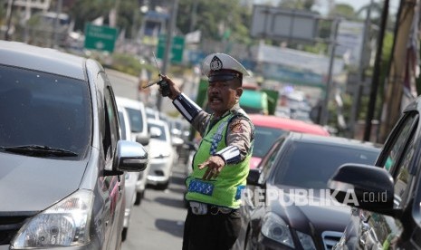 Petugas kepolisian mengatur kendaraan menuju puncak yang terjebak kemacetan di Simpang Gadog, Bogor, Jawa Barat, Jumat (6/5).  (Republika/Rakhmawaty La'lang)