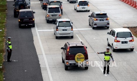 Petugas kepolisian mengatur kendaraan pemudik menuju pintu keluar Tol Cipali, Jawa Barat, Sabtu (2/7). (Republika/Wihdan Hidayat)