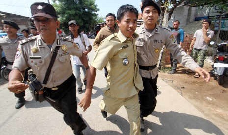 Petugas kepolisian mengevakuasi Kepala Desa Lebak Wangi Mursan (tengah) dari serangan warganya sendiri di Sepatan, Tangerang, Selasa (7/5). Warga menduga Musran mengetahui perbudakan buruh di pabrik panci milik kakak iparnya