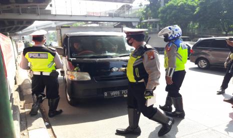 Petugas kepolisian menghentikan kendaraan yang melanggar rambu lalu lintas di Jalan DI Panjaitan, Jaktim, Sabtu (25/7).