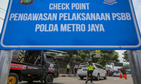 Petugas kepolisian menghentikan kendaraan yang melintas di perbatasan Tangerang-Jakarta di Jalan Daan Mogot, Jakarta, Jumat (10/4/2020). Polisi mengingatkan pengendara untuk selalu menggunakan masker dan aturan penumpang sesuai regulasi Pembatasan Sosial Berskala Besar (PSBB) di DKI Jakarta.