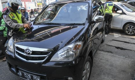 Petugas kepolisian menghentikan mobil berplat nomor genap yang memasuki Jalan Salemba Raya, di Matraman, Jakarta, Senin (9/9/2019). Petugas kepolisian mulai memberlakukan penindakan berupa tilang terhadap pengendara mobil yang melanggar di kawasan perluasan sistem ganjil-genap. 