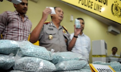  Petugas kepolisian menunjukan tiga orang tersangka beserta barang bukti berupa narkoba jenis shabu dan ecstasy saat jumpa pers di Polres Jakarta Barat, Selasa (19/6). (Prayogi/Republika)