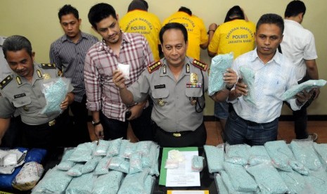  Petugas kepolisian menunjukan tiga orang tersangka beserta barang bukti berupa narkoba jenis shabu dan ecstasy saat jumpa pers di Polres Jakarta Barat, Selasa (19/6). (Prayogi/Republika)