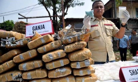 Petugas kepolisian menunjukkan barang bukti narkoba saat pemusnahan barang bukti narkoba di lapangan Polsek Palmerah, Jakarta Barat, Jumat (13/9).    (Republika/Prayogi)