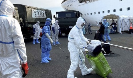 Petugas kesehatan bersiap menyemprotkan cairan disinfektan kepada WNI ABK Diamond Princess dan barang bawaan saat turun dari kapal di Yokohama, Jepang, Minggu (2/3/2020). Pemerintah mengevakuasi 69 WNI ABK Diamond Princess yang dinyatakan negatif COVID-19 untuk dipulangkan ke tanah air dan diobservasi di pulau Sebaru Kecil, Kepulauan Seribu.