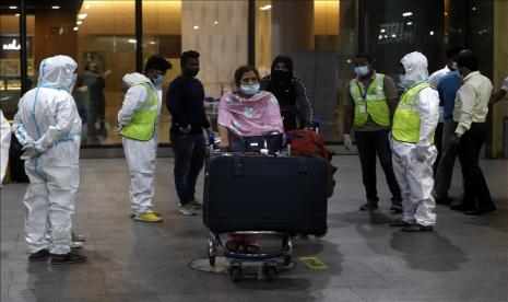 Petugas kesehatan India mengenakan pelindung diri memandu penumpang di Bandara Internasional Chhatrapati Shivaji Maharaj di Mumbai, India