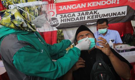 Petugas kesehatan melakukan tes cepat antigen kepada pemudik saat penyekatan larangan mudik Lebaran 2021 di akses keluar Jembatan Suramadu, Surabaya, Jawa Timur, Sabtu (15/5/2021). Sejumlah pemudik dari Pulau Madura menuju Surabaya yang terjaring dalam penyekatan tersebut dilakukan tes cepat antigen sebagai upaya pencegahan penularan COVID-19. 