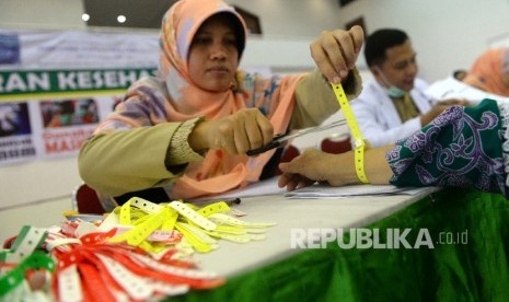 Petugas kesehatan memasang gelang kepada jamaah calon haji.