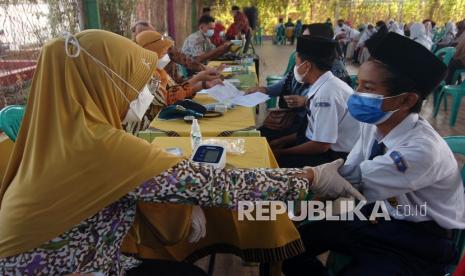 Petugas kesehatan memeriksa kesehatan sebelum menyuntikkan vaksin Covid-19 kepada pelajar SMP.