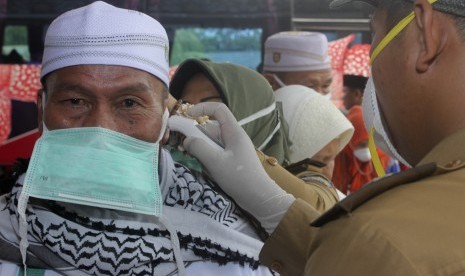  Petugas kesehatan memeriksa suhu tubuh seorang haji dengan alat pengukur saat kedatangan jamaah haji di Asrama Haji Provinsi Bengkulu, Kamis (8/10). 