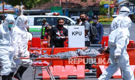 Petugas kesehatan mengangkat pemilih yang pingsan saat simulasi Pemilihan Kepala Daerah di Banyuwangi, Jawa Timur, Senin (14/9/2020). Simulasi tersebut digelar untuk menyiapkan segala hal yang diperlukan untuk penyelenggaraan Pilkada serentak pada 9 Desember 2020 di tengah wabah Covid-19. 