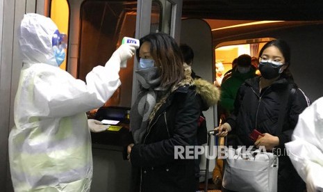 Petugas kesehatan mengenakan pakaian anti bahan berbahaya (hazardous material suit) memerilksa suhu tubuh penumpang yang datang dari daerah Wuhan di  Bandara Beijing, China.  Wabah Virus Wuhan di China telah memakan korban 17 orang meninggal dan ratusan lainnya positif terjangkit.