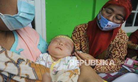 Petugas kesehatan mengukur lingkar kepala bayi di Posyandu (ilustrasi).  Bayi berjenis kelamin perempuan yang baru saja dilahirkan meninggal dunia setelah terkonfirmasi positif Covid-19 akibat tertular dari orang tuanya (ibu) yang merupakan pasien positif virus mematikan ini.