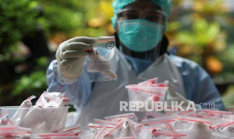 Petugas kesehatan menunjukkan sampel tes Swab PCR Covid-19 untuk guru dan siswa saat pelacakan klaster sekolah. (Ilustrasi)