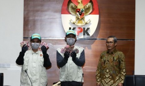 Petugas KPK menunjukkan barang bukti disaksikan oleh Wakil Ketua KPK Alexander Marwata (kanan) seusai memberikan keterangan pers terkait Operasi Tangkap Tangan (OTT) kasus dugaan suap jaksa di Gedung KPK, Jakarta, Selasa (20/8/2019). 