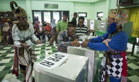 Petugas KPPS dengan pakaian tokoh pewayangan membantu warga memasukkan surat suara dalam Pemilu Legislatif di TPS 05 Ponggalan, Giwangan, Umbulharjo, Yogyakarta, Rabu (9/4).(Antara/Sigid Kurniawan)