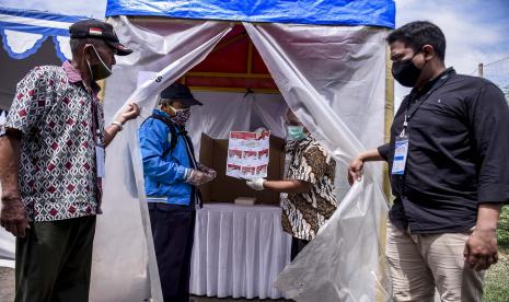 Petugas KPPS mendampingi warga yang suhu tubuhnya di atas normal untuk melakukan pencoblosan di Bilik Khusus saat simulasi pemungutan dan penghitungan suara Pilkada 2020 di Baleendah, Kabupaten Bandung.