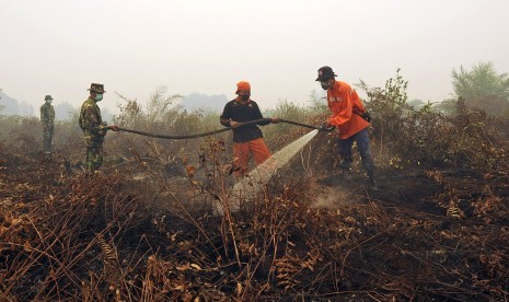 Petugas Manggala Agni dan TNI memadamkan sisa api yang membakar lahan gambut di Petaling, Muaro Jambi, Selasa (15/9).