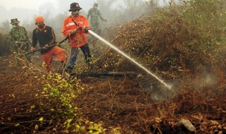 Petugas Manggala Agni dan TNI memadamkan sisa api yang membakar lahan gambut di Petaling, Muaro Jambi, Selasa (15/9).