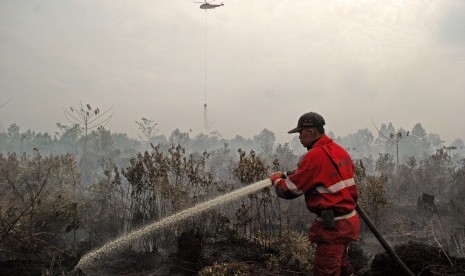  Petugas Manggala Agni dibantu Helikopter Badan Nasional Penanggulangan Bencana (BNPB) berusaha memadamkan api yang membakar lahan gambut di Pekanbaru, Riau, Senin (3/8).