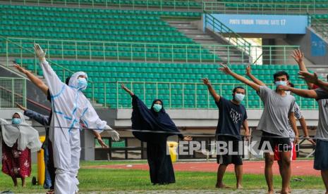 Petugas medis (kiri) memimpin senam pagi bersama pasien COVID-19 berstatus Orang Tanpa Gejala (OTG) di Stadion Patriot Chandrabhaga, Bekasi, Jawa Barat, Senin (28/9/2020). Olahraga pagi yang dilakukan rutin setiap hari oleh 25 pasien tersebut untuk meningkatkan imunitas tubuh selama menjalankan isolasi. 