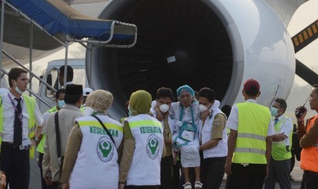 Petugas medis mengangkat seorang jamaah haji yang sakit saat tiba di Bandar Udara Sultan Hasanuddin, Makassar, Sulawesi Selatan, Selasa (29/9). 