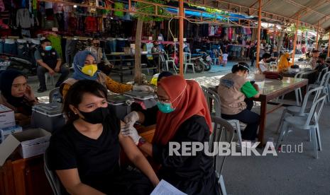 Petugas medis menyuntikkan cairan vaksin kepada seorang pengunjung pasar pada vaksinasi COVID-19 di Pasar Tradisional Manonda, Palu, Sulawesi Tengah, Sabtu (22/1/2022). Selain melayani vaksin dosis pertama dan kedua, vaksinasi COVID-19 yang difasilitasi Polres dan Dinas Kesehatan setempat itu juga melayani vaksin booster atau dosis ketiga untuk memperluas cakupan vaksin mempercepat kekebalan komunal.