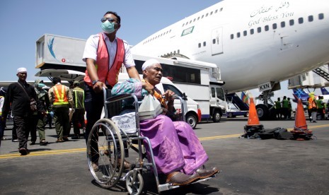 Petugas medis merawat seorang jamaah haji yang mengalami sakit saat tiba di tanah air di Bandara Internasional Juanda Surabaya di Sidoarjo, Jawa Timur, Minggu (18/9).