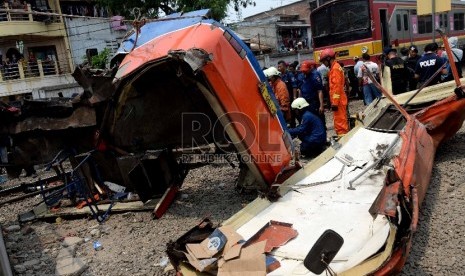 Petugas melakukan evakuasi bangkai Bus Metromini pascatabrakan dengan KRL di Kawasan Stasiun Angke, Jakarta Barat, Ahad (6/12).  (Republika/WIhdan)