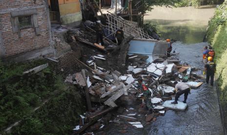 Petugas melakukan evakuasi barang-barang dari rumah warga yang roboh karena tergerus aliran sungai di Kampung Nayu, Banjarsari, Solo, Jawa Tengah, Senin (9/5/2022). Wali Kota Solo Gibran Rakabuming Raka menjanjikan perbaikan rumah warga yang mengalami kerusakan tersebut dan memastikan Pemkot Solo akan melakukan penertiban serta penataan bangunan di sepanjang bantaran sungai di Solo karena beresiko tinggi.